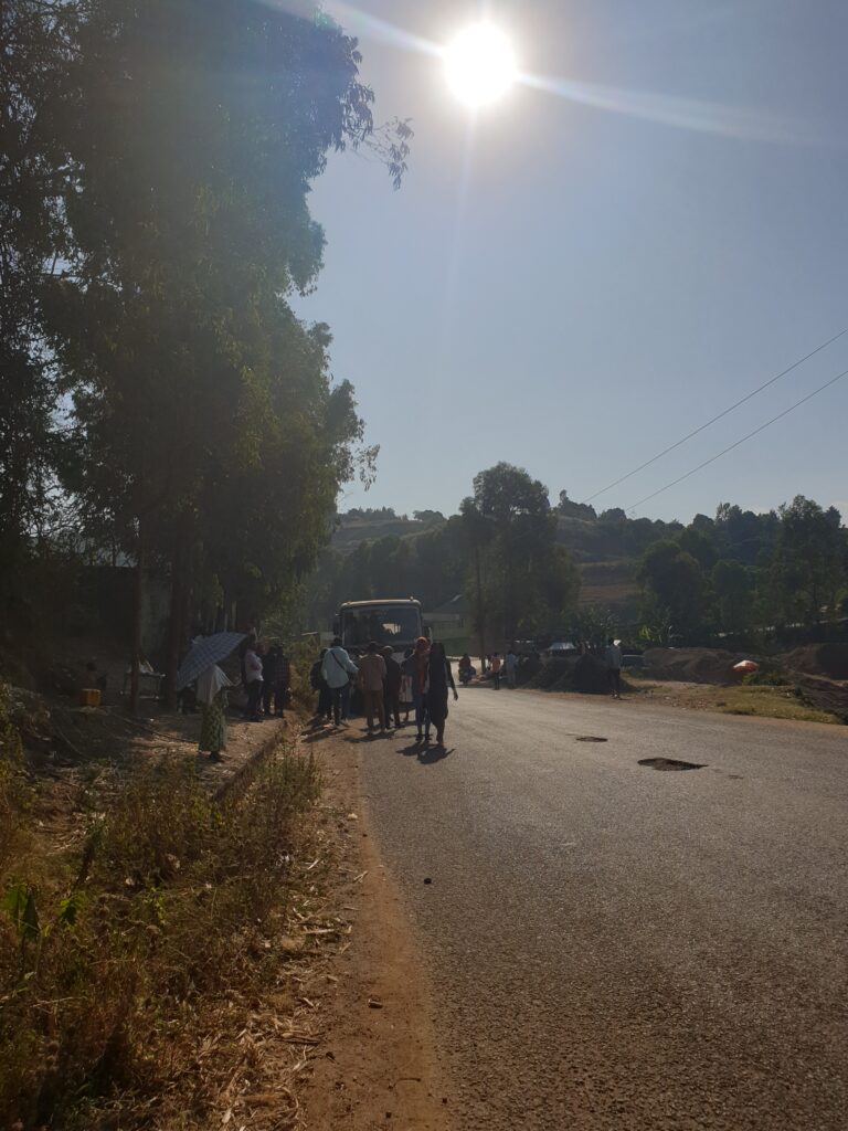 Près de la base de la Monusco, à Msara. Un autobus vient de s'arrêter. Les étudiants venus de Kalambo descendent et se mettent à marcher. Le soleil est ardent. De la verdure tout autour. Profession : étudiant de Kalambo.