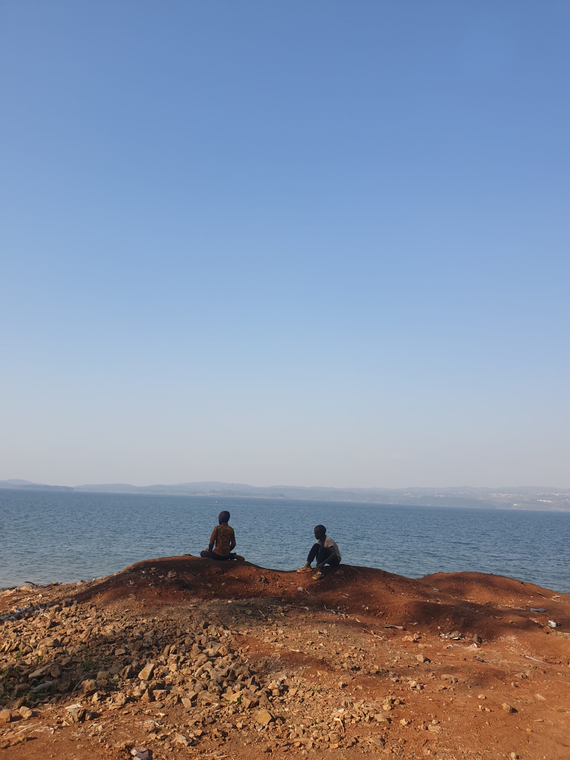 Deux jeunes garçons assis au bord du lac Kivu. Les étudiants observent. Bukavu, RD Congo. Le ciel, le lointain. Profession : étudiant de Kalambo.